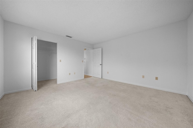 unfurnished bedroom with baseboards, light colored carpet, visible vents, and a textured ceiling