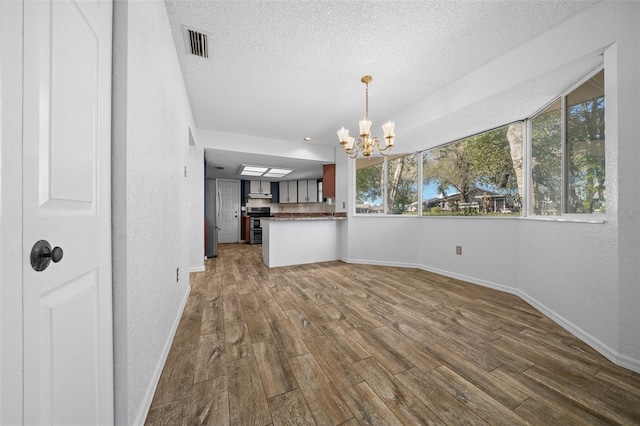 interior space with a chandelier, visible vents, a textured ceiling, and dark wood-style flooring