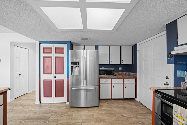 kitchen with a textured ceiling, visible vents, wood tiled floor, under cabinet range hood, and appliances with stainless steel finishes