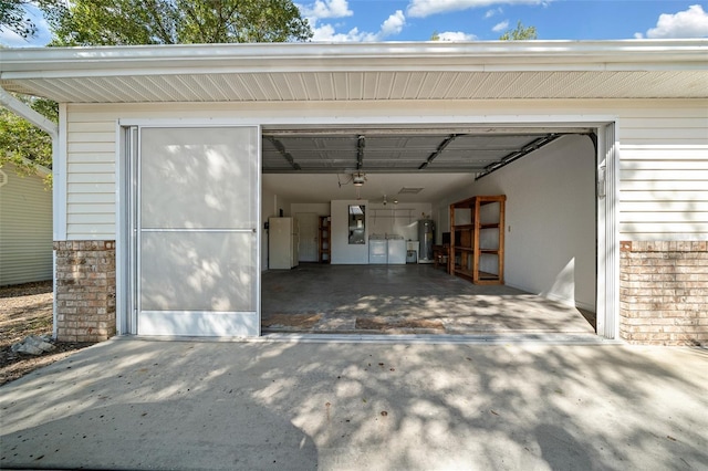 garage with concrete driveway, a garage door opener, water heater, and freestanding refrigerator