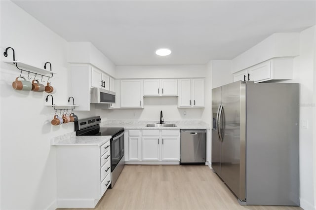 kitchen with white cabinetry, sink, stainless steel appliances, and light hardwood / wood-style floors