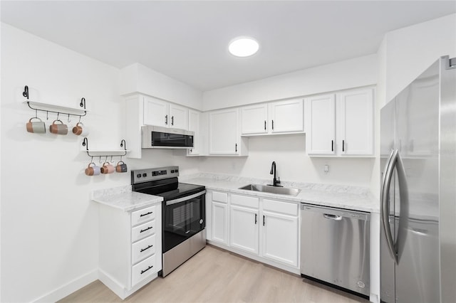 kitchen featuring stainless steel appliances, white cabinetry, sink, and light hardwood / wood-style flooring