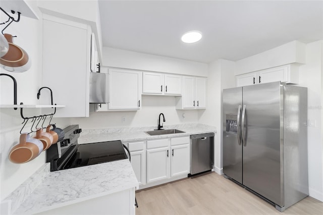 kitchen featuring sink, white cabinetry, light stone counters, light hardwood / wood-style flooring, and stainless steel appliances