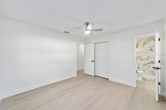 unfurnished bedroom featuring ceiling fan, connected bathroom, light hardwood / wood-style floors, and a closet