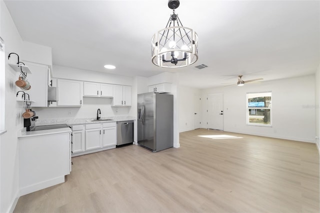 kitchen with sink, white cabinetry, hanging light fixtures, stainless steel appliances, and light hardwood / wood-style floors