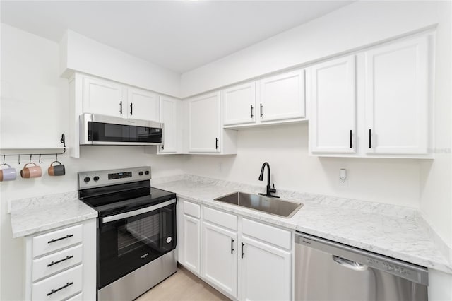 kitchen with white cabinetry, sink, light stone counters, and appliances with stainless steel finishes