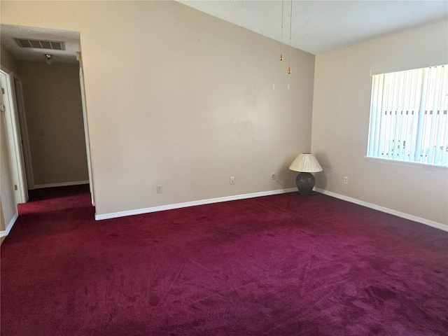 unfurnished room featuring vaulted ceiling and dark colored carpet