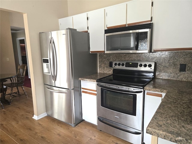 kitchen featuring appliances with stainless steel finishes, white cabinets, light hardwood / wood-style floors, and decorative backsplash