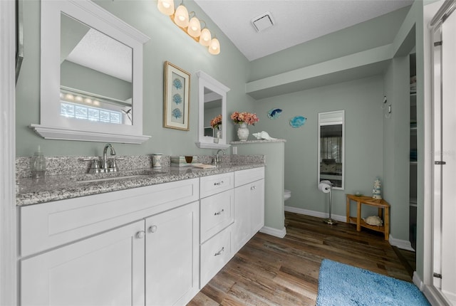 bathroom with hardwood / wood-style flooring, vanity, toilet, and a textured ceiling