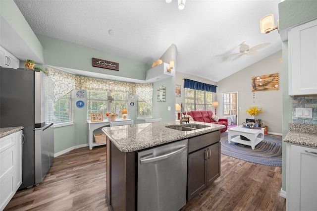 kitchen with lofted ceiling, sink, white cabinetry, stainless steel appliances, and light stone countertops