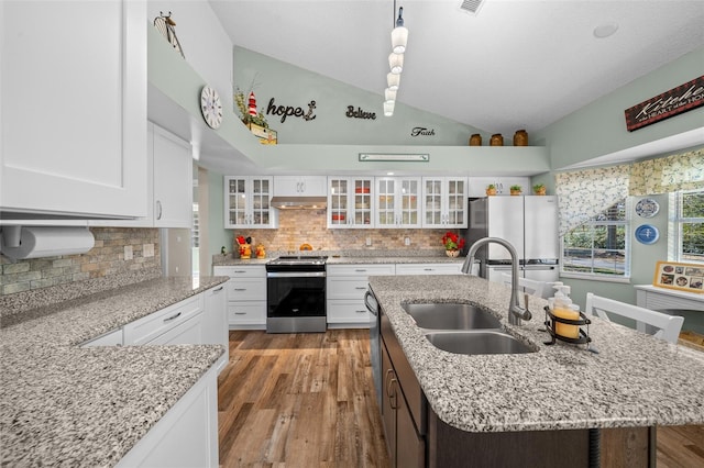 kitchen featuring vaulted ceiling, appliances with stainless steel finishes, sink, white cabinets, and a center island with sink