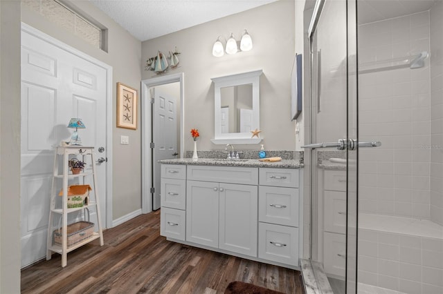 bathroom featuring vanity, a textured ceiling, a shower with shower door, and wood-type flooring