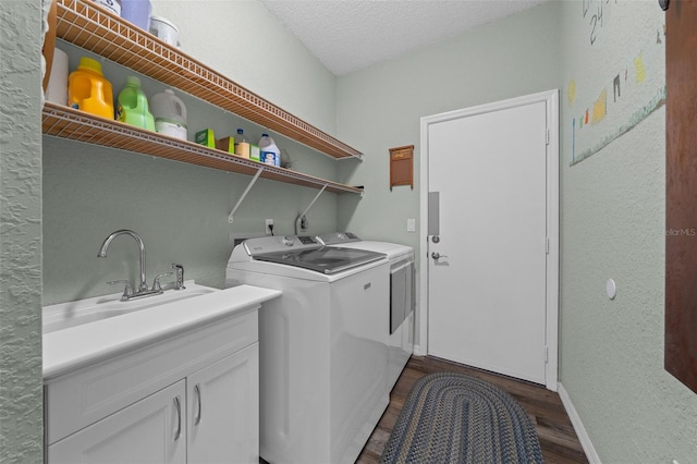 clothes washing area featuring sink, cabinets, washer and dryer, a textured ceiling, and dark hardwood / wood-style flooring