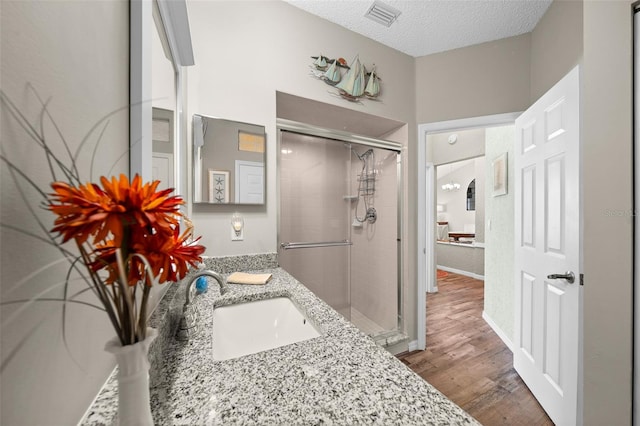 bathroom with a shower with door, vanity, hardwood / wood-style flooring, and a textured ceiling