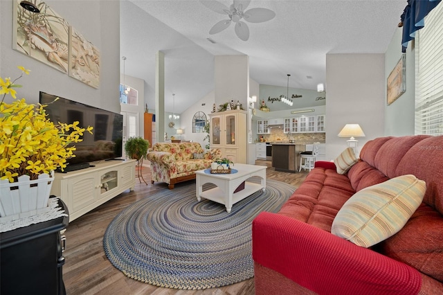 living room with a textured ceiling, high vaulted ceiling, dark hardwood / wood-style floors, and ceiling fan