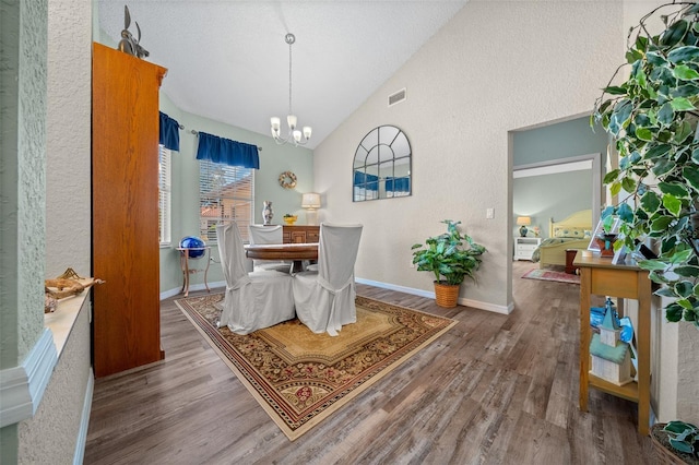 dining space featuring hardwood / wood-style flooring, a notable chandelier, and high vaulted ceiling