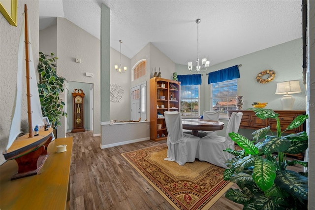 dining room with an inviting chandelier, wood-type flooring, high vaulted ceiling, and a textured ceiling