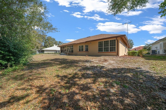 rear view of property featuring a yard and central AC unit