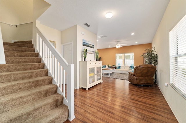 stairway with a wealth of natural light, wood-type flooring, and ceiling fan