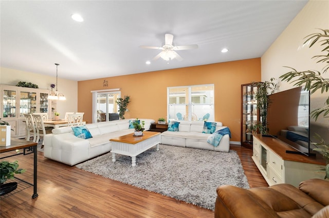 living room with hardwood / wood-style flooring and ceiling fan with notable chandelier