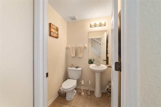 bathroom featuring tile patterned floors, a textured ceiling, and toilet