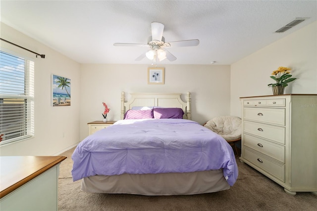 bedroom featuring ceiling fan, light colored carpet, and a textured ceiling