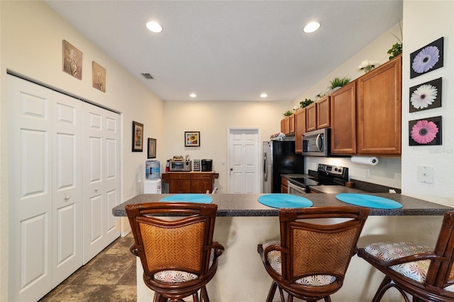 kitchen featuring appliances with stainless steel finishes, a kitchen bar, and kitchen peninsula