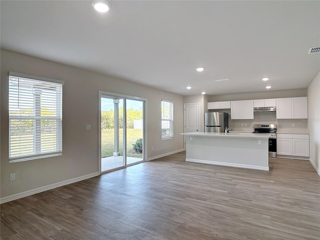 kitchen featuring a kitchen island with sink, a healthy amount of sunlight, white cabinets, and appliances with stainless steel finishes