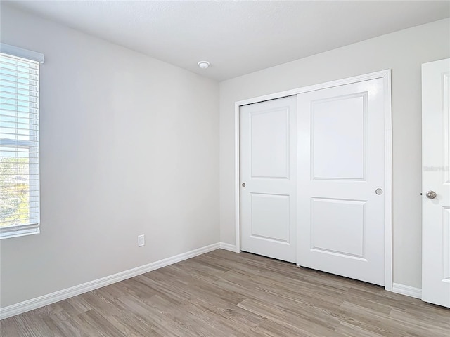 unfurnished bedroom with a closet and light wood-type flooring