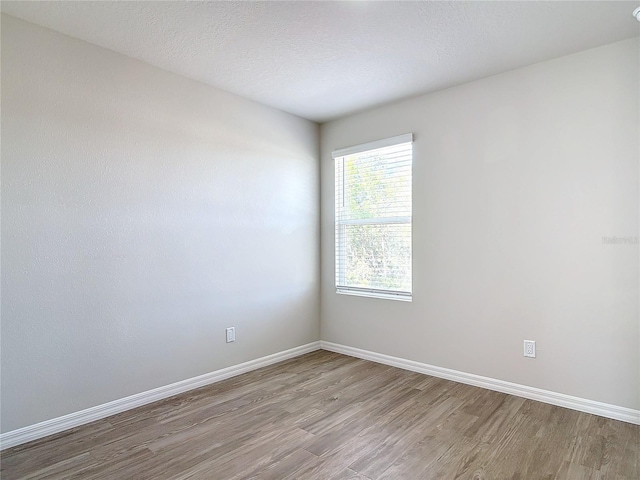 spare room featuring light hardwood / wood-style floors and a textured ceiling