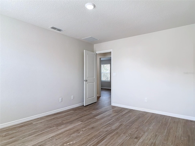 empty room with hardwood / wood-style flooring and a textured ceiling