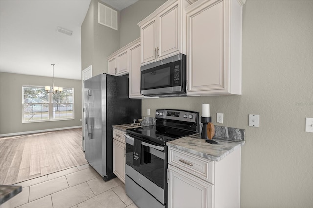 kitchen with white cabinetry, light tile patterned floors, stainless steel appliances, and an inviting chandelier