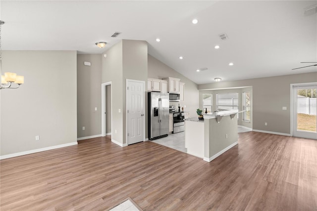 kitchen featuring appliances with stainless steel finishes, a breakfast bar, light hardwood / wood-style floors, and white cabinets