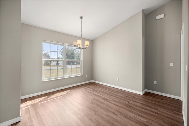 spare room with an inviting chandelier, dark wood-type flooring, and lofted ceiling