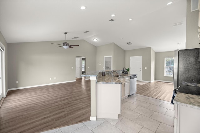 kitchen featuring lofted ceiling, sink, light stone counters, white cabinetry, and appliances with stainless steel finishes