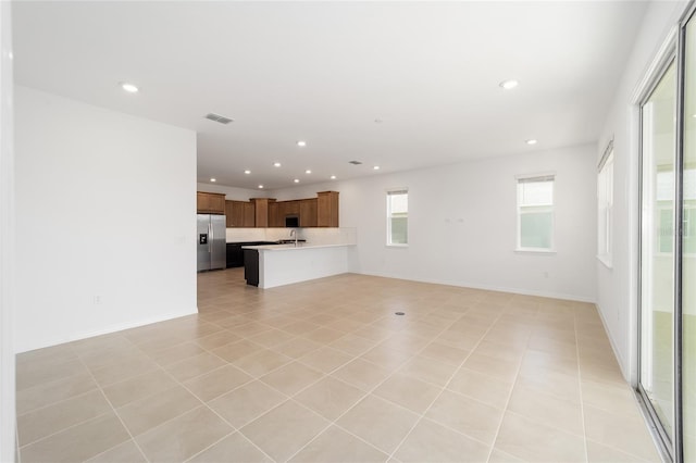 unfurnished living room featuring light tile patterned flooring and sink