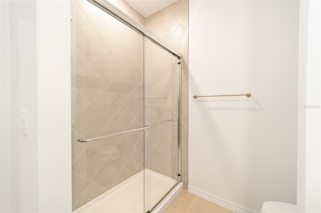 bathroom featuring tile patterned floors, toilet, and a shower with shower door