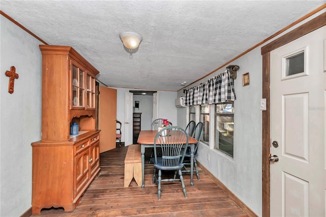 dining space with wood-type flooring, crown molding, a textured ceiling, and baseboards