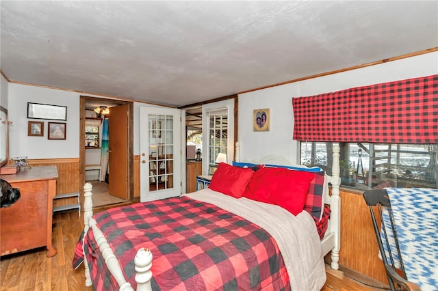 bedroom with wainscoting, crown molding, baseboard heating, and wood finished floors