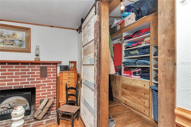 interior space with crown molding, visible vents, a barn door, a brick fireplace, and wood finished floors