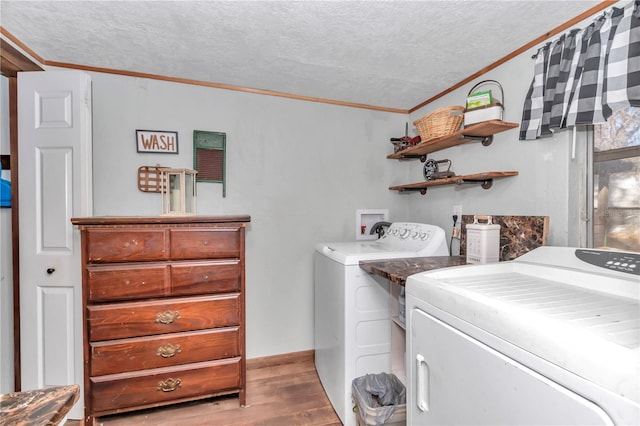 clothes washing area featuring crown molding, washer and clothes dryer, a textured ceiling, wood finished floors, and laundry area