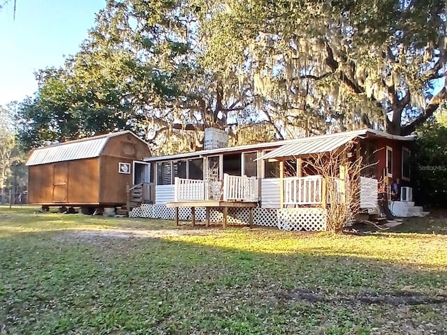 back of house featuring metal roof, a storage shed, an outdoor structure, a gambrel roof, and a yard