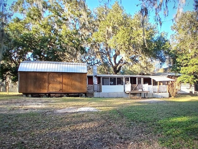 rear view of house featuring a sunroom, a yard, a deck, and metal roof