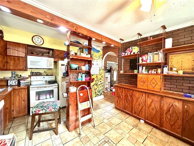 kitchen featuring white appliances, ornamental molding, a textured ceiling, and brick wall