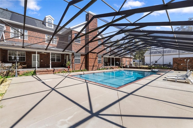 view of swimming pool featuring glass enclosure and a patio