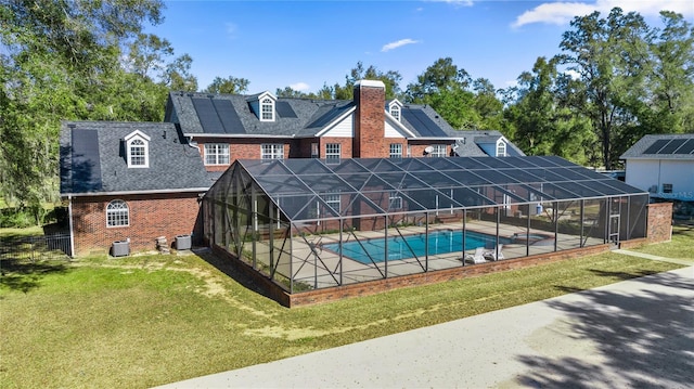 view of pool featuring a yard, central AC unit, a patio area, and glass enclosure