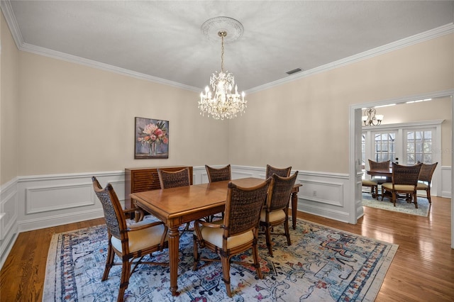 dining area with an inviting chandelier, crown molding, and wood-type flooring