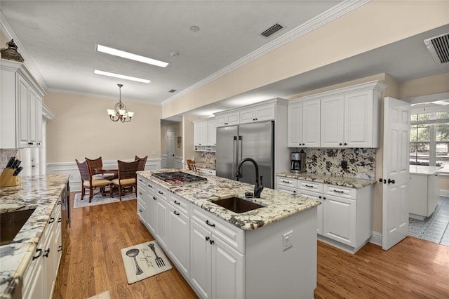 kitchen featuring pendant lighting, sink, appliances with stainless steel finishes, an island with sink, and white cabinets