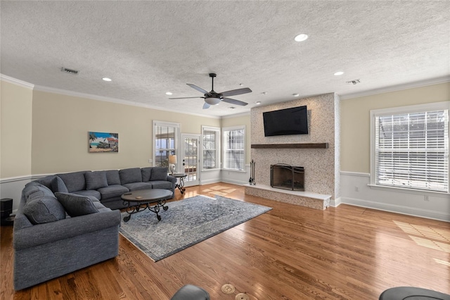 living room with ornamental molding, a healthy amount of sunlight, a fireplace, and light hardwood / wood-style floors