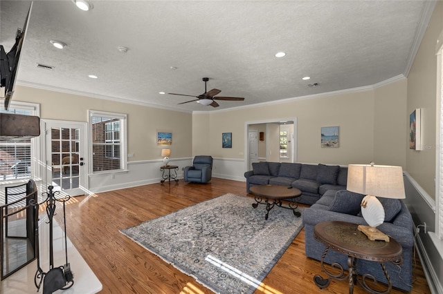 living room featuring crown molding, ceiling fan, a textured ceiling, and light wood-type flooring